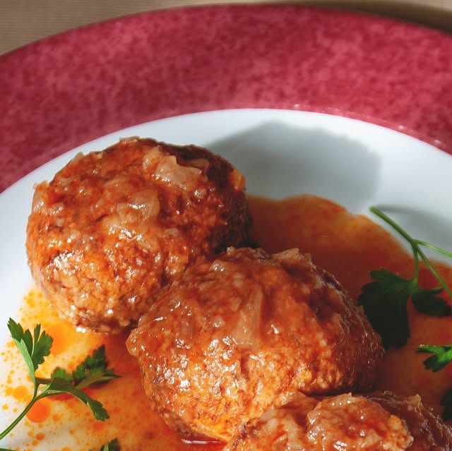 Plato de guiso en salsa con perejil, servido en loza roja