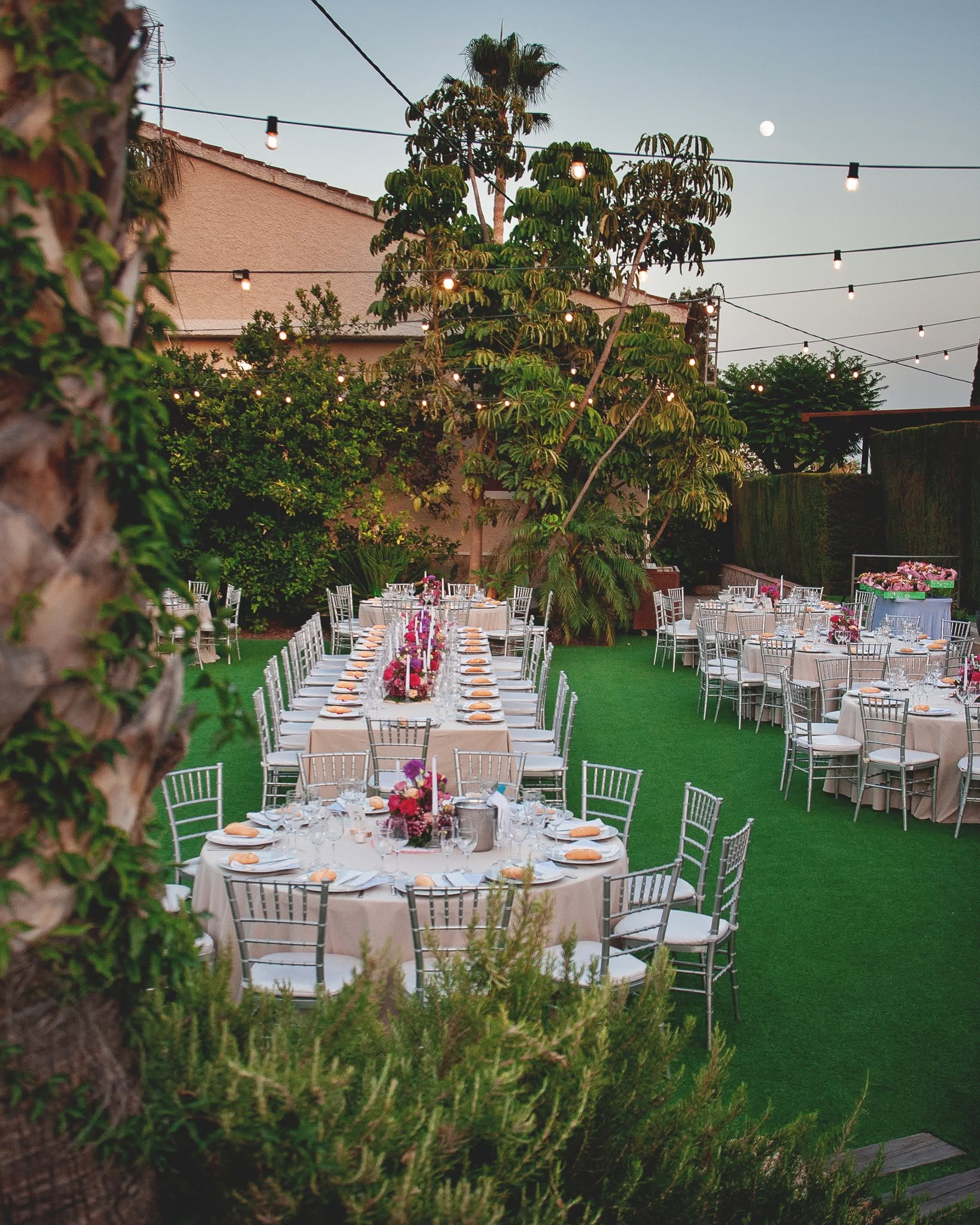 El jardín del restaurante al anochecer, con las mesas vestidas y las guirnaldas de bombillas encendidas
